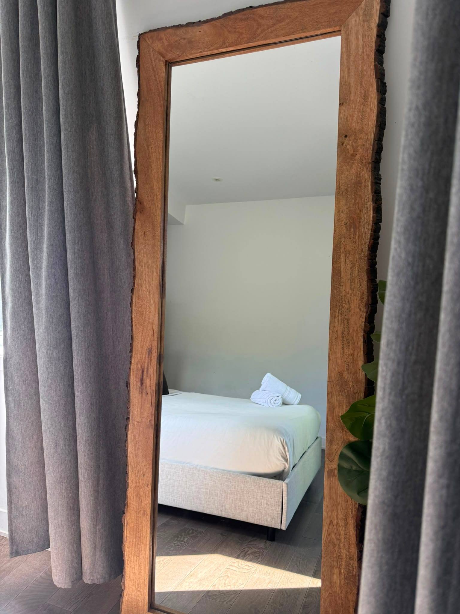 Bedroom seen in a standing mirror, towels folded on the bed